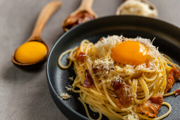 Carbonara pasta. Spaghetti with pancetta, egg, parmesan and cheese. Traditional italian cuisine. Close-up grey background