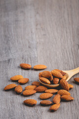 almonds on wooden table with wood spoon