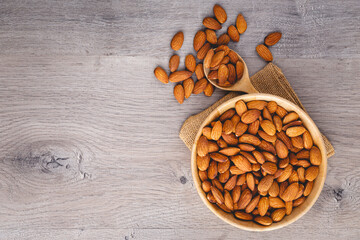 Top view of almonds on wooden table with wood spoon or scoop. Almond in wooden bowl