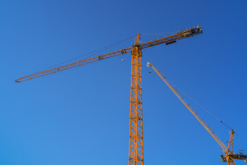 Tower cranes at building site against a blue sky in London