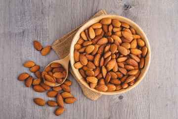 Top view of almonds on wooden table with wood spoon or scoop. Almond in wooden bowl