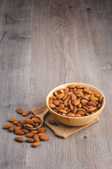 almonds on wooden table with wood spoon or scoop. Almond in wooden bowl