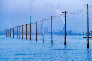 朝焼けの海から伸びる日本の電柱