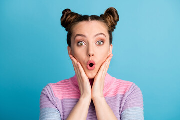 Closeup photo of attractive excited lady two funny buns open mouth crazy youngster hold arms on cheekbones amazed wear casual warm sweater isolated blue color background