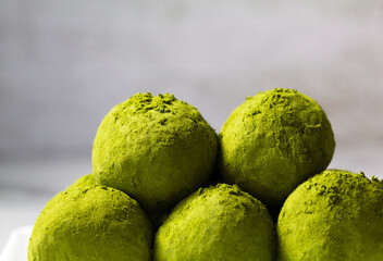 Homemade energy balls with dried apricots, raisins, dates, prunes, walnuts, pistachios and green matcha. Healthy sweet food. Energy balls a marble grey background. Close up. Side view.
