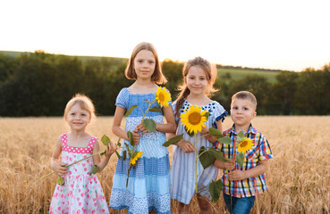 four kids with sunflowers in field