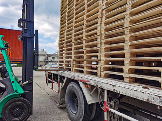 Naklejka premium Worker driving forklift to loading and unloading wooden pallets from truck to warehouse cargo storage, shipment in logistics and transportation industrial, wood pallets stack