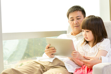 Father and daughter using tablet together at home