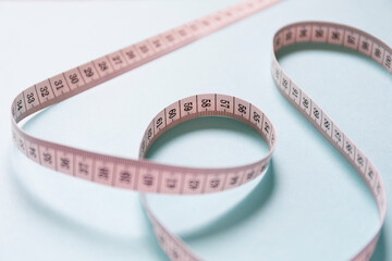 ランダムな形で置かれたピンク色の巻尺　水色の背景