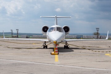 White small turbofan-powered business jet airplane on the apron of an airport. Fast modern aircraft for air transportation. Aviation technology. Travel and business concept.
