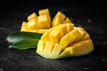 Macro shot of the fresh mango tropical fruit cut in cubes on the dark background