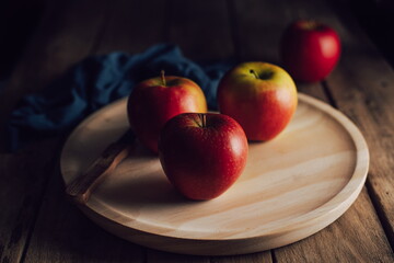 still life of apples on rustic table and black background, dark food