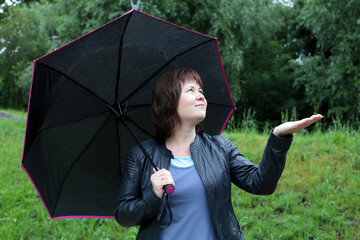 Rainy weather, woman with black umbrella checks if the rain has stopped
