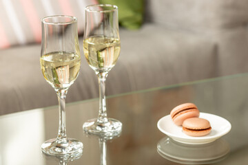 Glasses of sparkling champagne with macarons, close up. Warm colored. Celebration event, holidays, drinks concept. Companion for best family or friend's memories. Anniversary, wedding day or Christmas