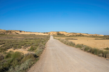 Desertic path into arid landscape and clear sky