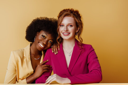 Diverse friendship: portrait of two beautiful happy smiling multiethnic women. Models wearing colorful blazers, jewelry. Different nation, multiracial friends concept. Copy, empty space for text