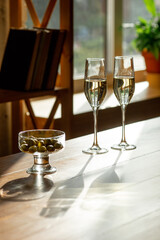 Glasses of sparkling champagne with snack, close up. Warm. Celebration event, holidays, drinks concept. Companion for best family or friend's memories. Anniversary, wedding day or Christmas time.