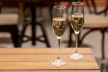 Glasses of sparkling champagne with bokeh, close up. Warm. Celebration event, holidays, drinks concept. Companion for best family or friend's memories. Anniversary, wedding day or Christmas time.