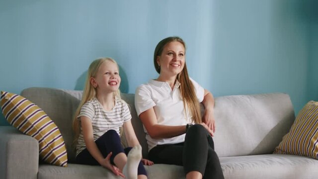 Parents are playing pantomime with their daughter at home, dad is showing a word, mom and child are guessing, all have great time together, happy family concept, Slow motion.