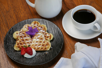 Belgian waffles served with tea on the wooden table
