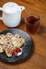 Belgian waffles served with tea on the wooden table
