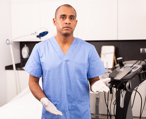 Fototapeta premium Professional experienced Hispanic male beautician welcoming in clinic of modern aesthetic medicine, telling about cosmetology treatments