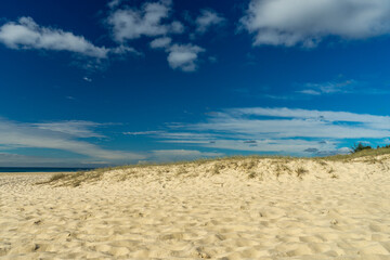 Sand dune with grass and beautiful blue sky at Currumbin Beach, Gold Coast, Queensland, Australia.