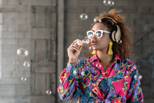 Black Woman In Sunglasses And Headphones Blowing Bubbles