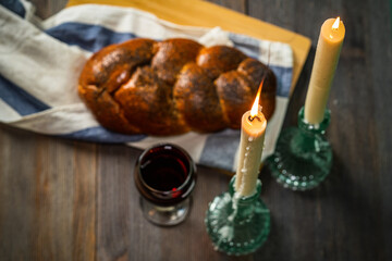 Shabbat Shalom. Challah bread, shabbat wine and candles on wooden table.