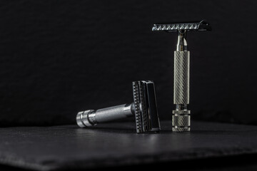 Metallic safety razors on dark background, barber shop concept