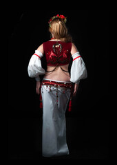 back view of woman in traditional red with white slavic costume holding hands hear hips isolated on black
