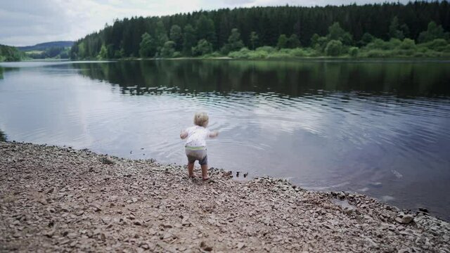 Baby girl throwing stone into water