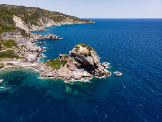 The church of Agios Ioannis on the Mamma Mia Cliff on the island of Skopelos, surrounded by the blue Mediterranean sea seen from above in drone view.