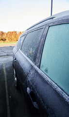 A frozen icy cold textured car in winter on a freezing morning, frozen windscreen. frozen solid in the windy freeze environment. frosty windows and black ice on the road. minus degrees.