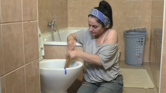 Woman using plunger in smelly toilet
