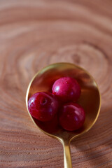 Ripe cherry berry on a wooden slice of wood in golden spoon