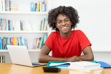 Laughing afro american male student learning at desk