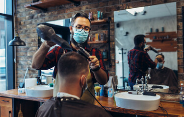 Hair cutting during pandemic. Young man have hair cutting at barber shop during pandemic isolation, they both wear protective equipment.