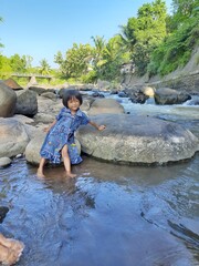Asian kid girls are standing and playing on the river and rocks in the beautiful village