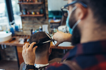 Hair cutting during pandemic. Young man have hair cutting at barber shop during pandemic isolation,...