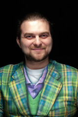 portrait of handsome positive stylish bearded man in green checkered blazer looking at camera isolated on black