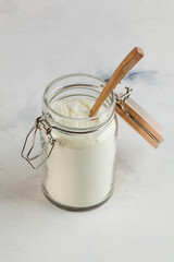 Transparent jar of white collagen powder with a wooden spoon. Skin care, rejuvenation. Copy space.