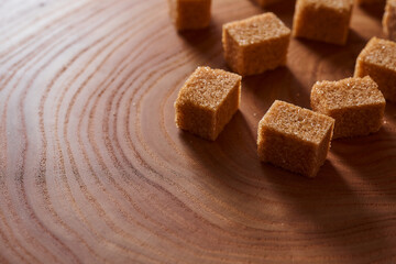Brown cane sugar pieces on a slice, a plank of wood. With copy space.