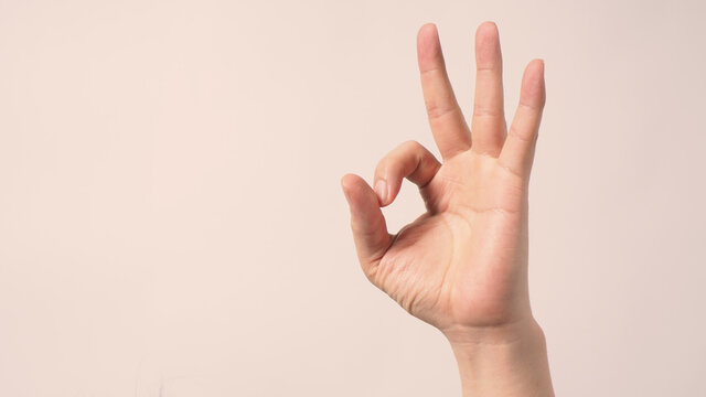 Man is doing A-Ok hand sign on white background.