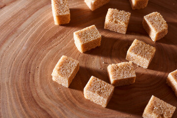 Brown cane sugar pieces on a slice, a plank of wood. With copy space.