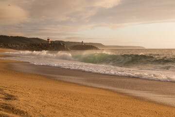 Sunset on the beach in Nazare, Portugal. Last lights on the beach with his two lighthouses in the background