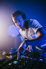 Vertical view of a Techno young Caucasian male DJ with his headphones playing music at a concert...