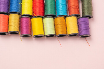 ピンクの背景のカラフルな縫い糸
