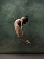 Freedom. Graceful classic ballerina dancing on dark studio background. Pastel bodysuit. The grace, artist, movement, action and motion concept. Looks weightless, flexible. Fashion, style.