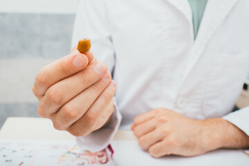 Intra-ear hearing aid close-up in a doctor's hand. Hearing solution, an audiologist holding a hearing aid, close-up.